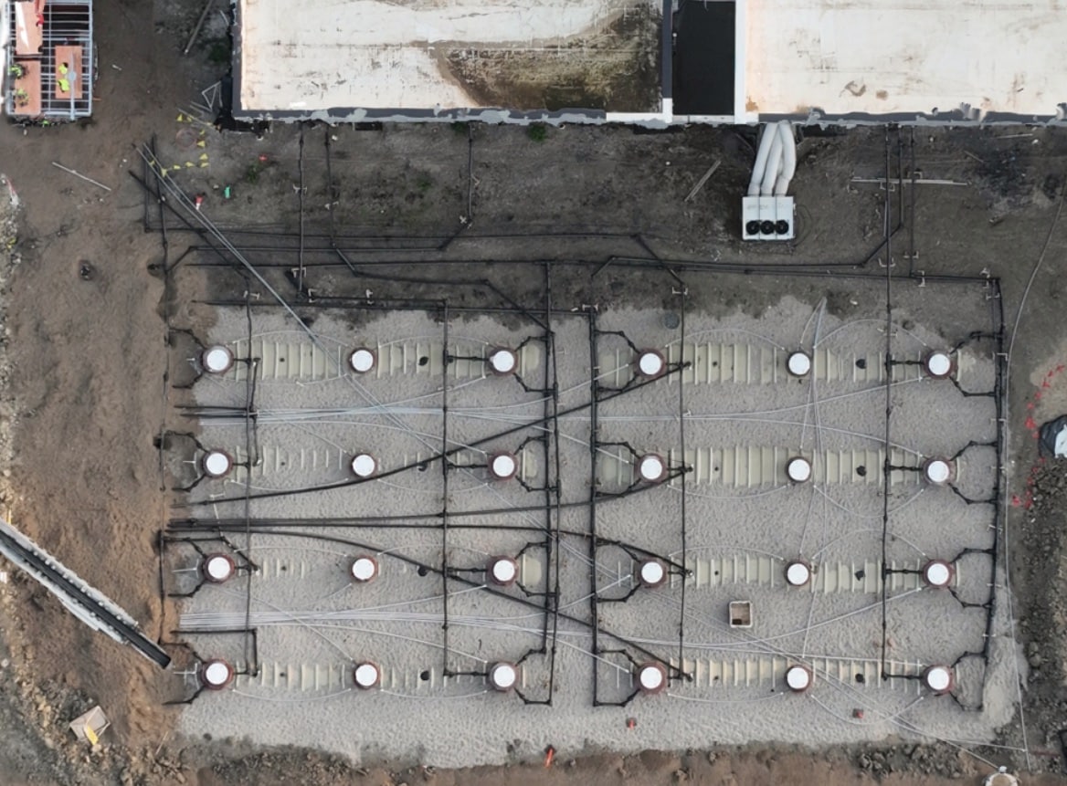 Aerial view of a data center fuel tank field beside the building, with tank risers and piping runs in place